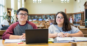 Two students study together in a library