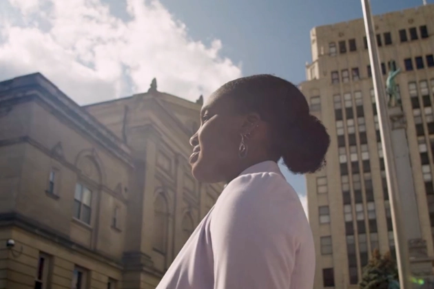 A Dell Scholar stands outside surrounded by tall buildings in a city.